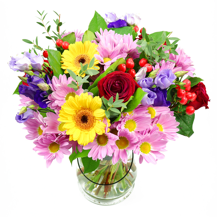 In this image, a lush mixed bouquet stands proudly in a cylindrical glass vase, its abundant blooms radiating outward against a plain white backdrop, much like a statement piece ready to brighten a Ruislip townhouse near the station. At its core, classic red roses open generously, their velvety petals spiralling into a rich, romantic heart that anchors the design. Flanking them, two golden yellow gerbera daisies with dark central discs shine brightly, their strong, daisy-like faces bringing a playful brightness and a modern, graphic note. Encircling these central flowers, layers of soft pink and lilac daisies or chrysanthemums spread in all directions, each small flower composed of many narrow petals surrounding pale yellow centres, creating a cushiony, almost cloud-like texture. Interlaced with this softness, stems of lisianthus in shades of purple-from deep, inky violet to gentle lavender-rise gracefully, their bell-shaped blossoms with slightly ruffled edges adding height and an air of elegance. Scattered around the arrangement are clusters of round red hypericum berries, their smooth surfaces catching subtle reflections, contributing both colour contrast and a contemporary feel. Various greens frame and support the blooms: broad, darker leaves provide structure and depth, while finer, more elongated sprigs in lighter greens stretch outward, suggesting natural growth, as if the bouquet were inspired by a walk through the greenery near Ruislip Woods. The clear vase reveals an orderly gathering of stems immersed in fresh water, showcasing the professional craftsmanship behind the design. Soft, even lighting brings out the vibrancy of each hue and creates a feeling of easy celebration, making this bouquet ideal as a centrepiece for family gatherings, birthdays, or quiet moments of appreciation in homes across Ruislip.